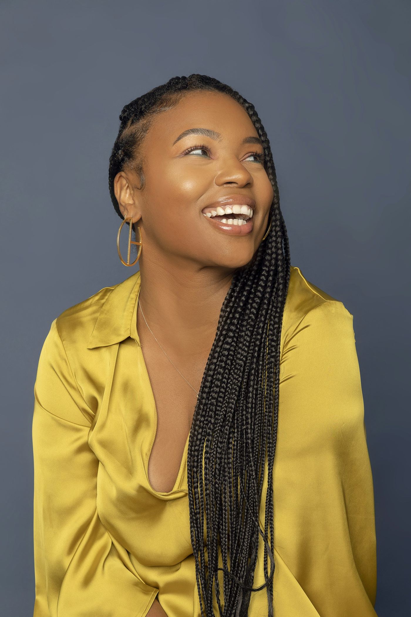 Smiling woman with long, neat braids in a gold blouse (sample photo)
